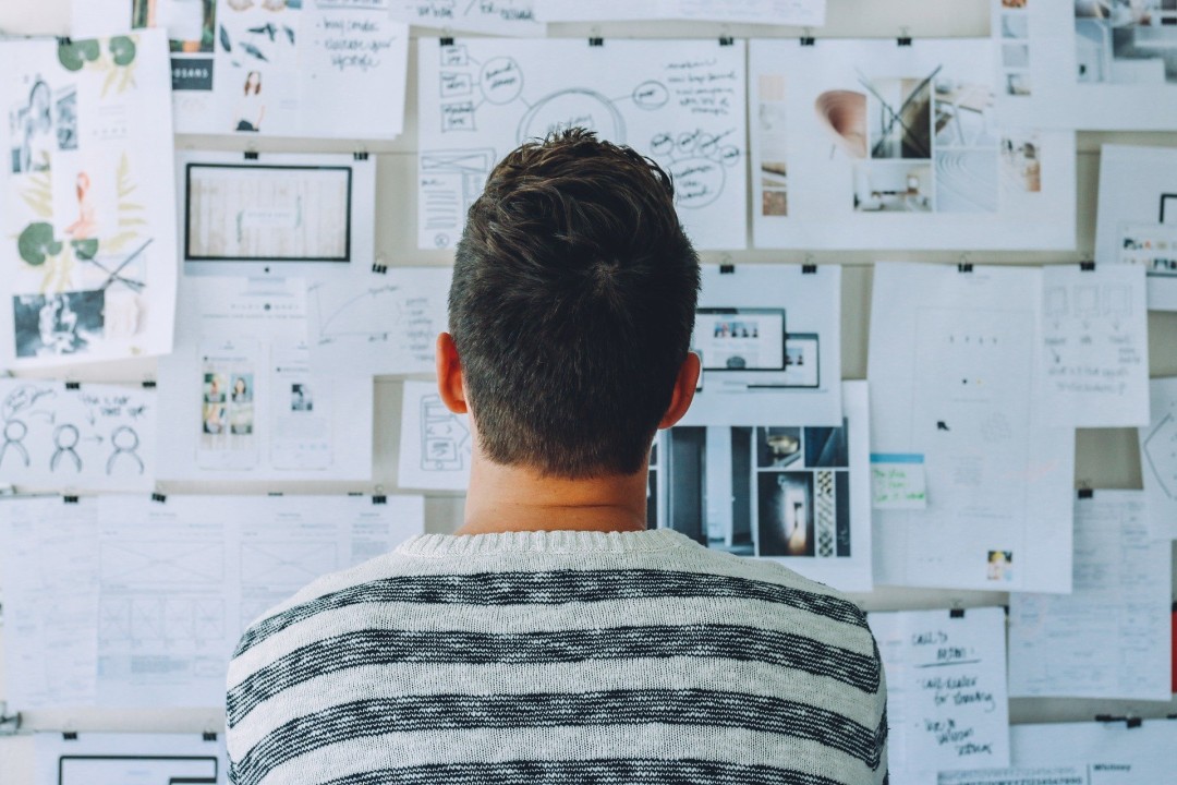 Man standing looking at board with lots of papers